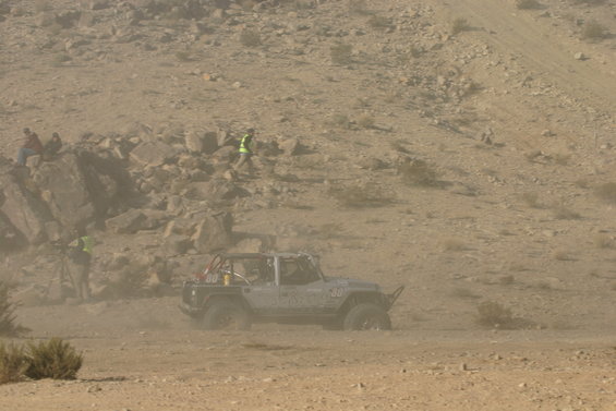 Silver Jeep Wrangler with number 80 on door, kicking up dust on a desert course