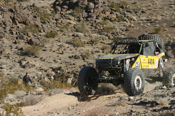 Yellow off-road buggy with large tires and roll cage, number 4404 visible on side, driving on dusty terrain