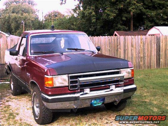 Maroon Ford pickup truck with black hood bra, parked outdoors
