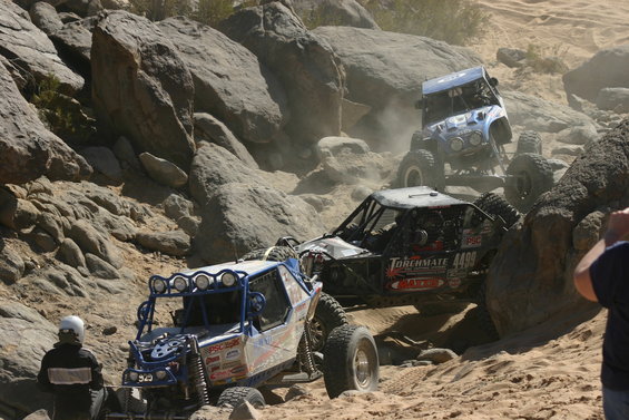 Three off-road buggies navigate a rocky, sandy trail. One buggy has 'TORCHMATE 4499' on its side