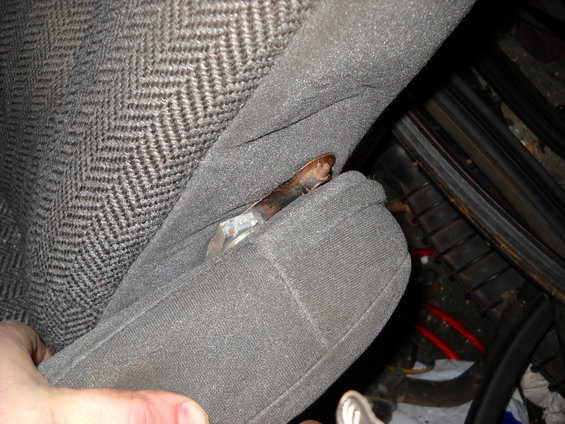 Close-up of gray patterned car seat fabric with a rusty metal lever visible