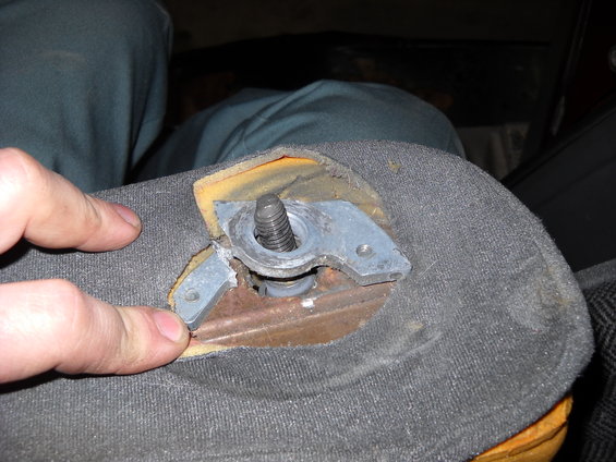 Close-up of a torn gray fabric armrest revealing a metal mounting bracket and bolt
