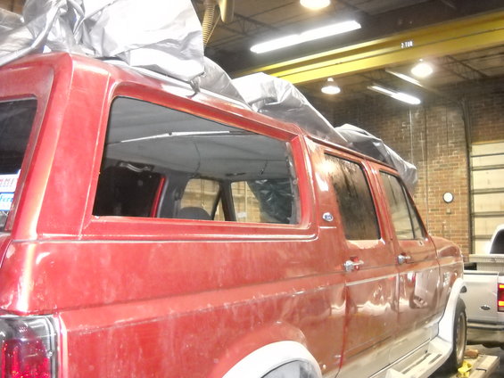 Red van with tarp on roof, side view, showing missing rear window and interior