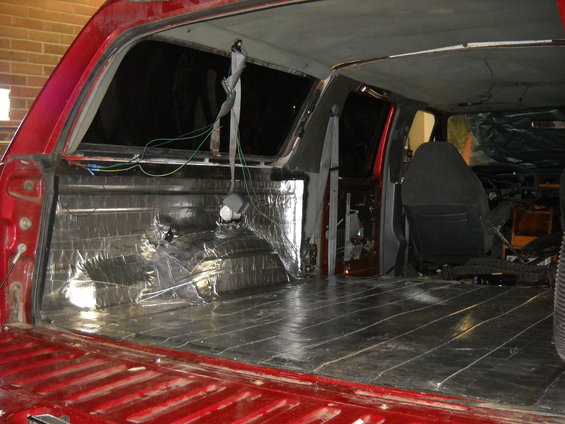 Interior of red truck with soundproofing on walls and floor. Seat visible
