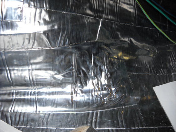 Shiny silver insulation material covers a wall, with some wires visible at the top right
