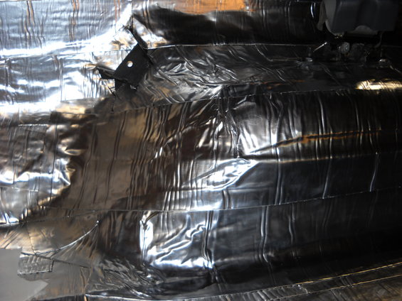 Shiny, crinkled insulation material covering the underside of a vehicle