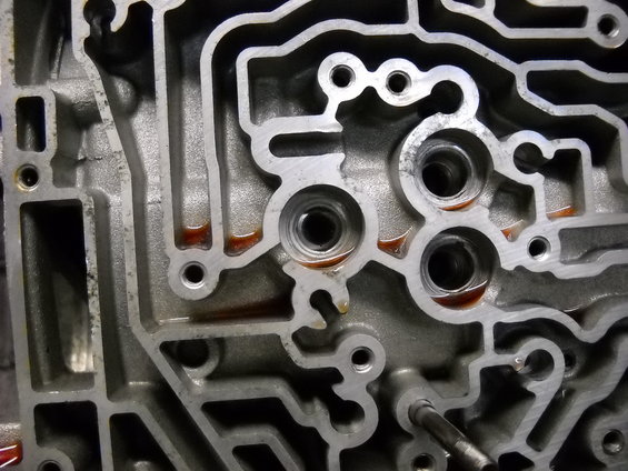 Close-up of an automatic transmission valve body with reddish fluid in channels