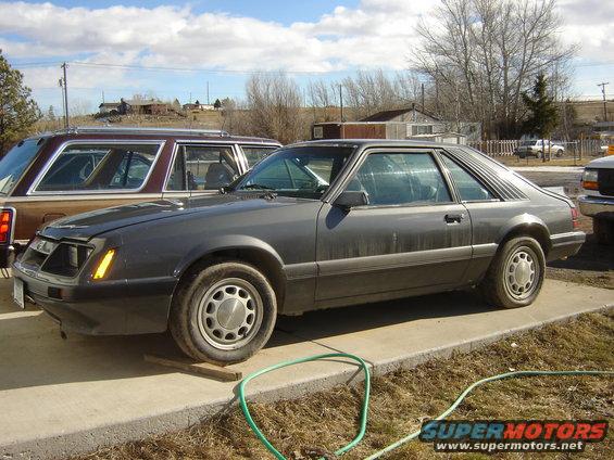 Gray 1986 Ford Mustang coupe parked outside next to a station wagon