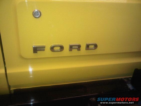 Close-up of 'FORD' lettering on a yellow vehicle's body panel