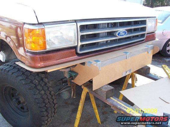 1989 Ford Bronco front end with a temporary cardboard bumper held by sawhorses
