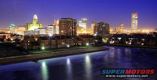 City skyline at night with buildings illuminated and reflected in the water