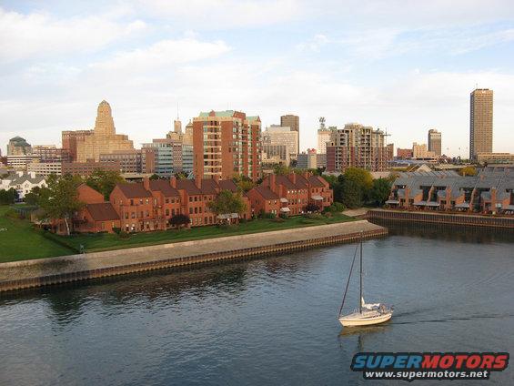 City skyline with waterfront buildings and a sailboat on the water