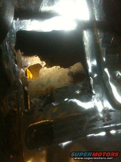Rusted metal interior with a hole showing yellow