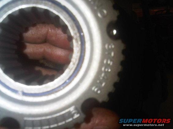 Close-up of a splined metal hub part with blue ring and stamped numbers