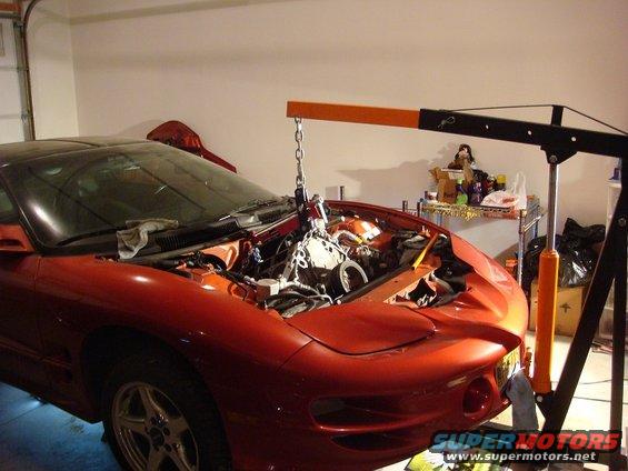 2001 Pontiac Trans Am engine bay with engine being lifted out by an engine hoist