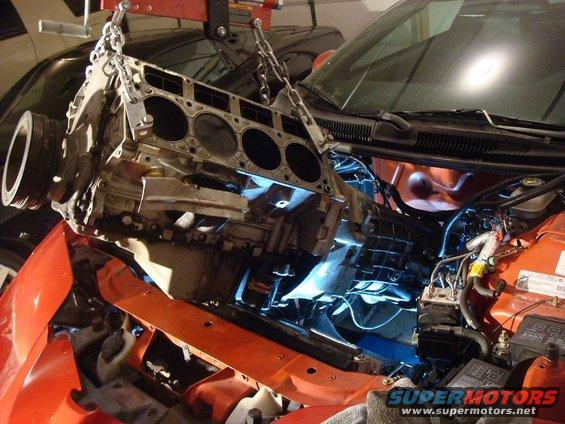 Orange 2001 Pontiac Trans Am with engine being removed by a hoist