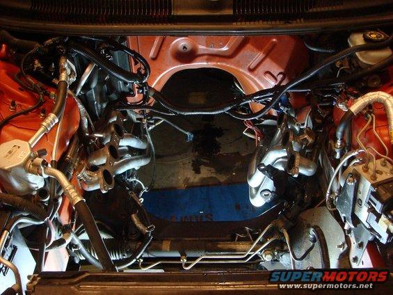 Engine bay with exhaust manifolds, wiring, and hoses visible