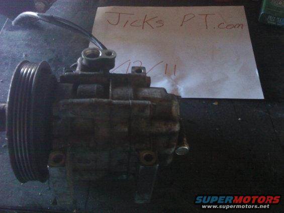 Air conditioning compressor with pulley and date 12/11 written on paper