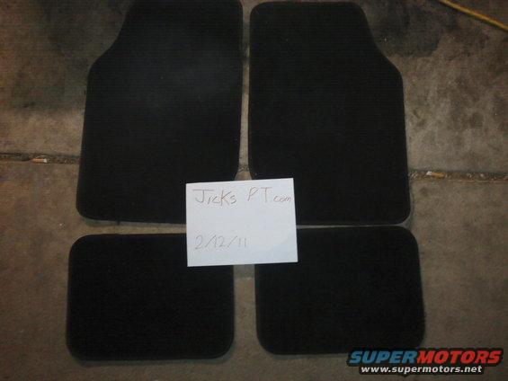 Four black car floor mats on a concrete floor, with a note that says "Jicks PT.com 2/12/11"