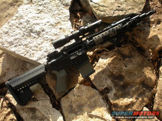 Assault rifle with scope and tactical grip rests on rocks