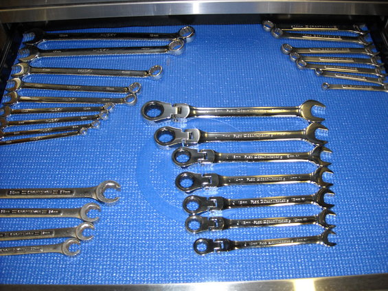 Several sets of wrenches, including Husky and Craftsman brands, laid out on a blue mat in a drawer