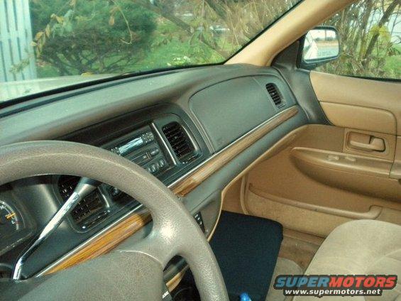 Tan interior of a 1997 Ford Crown Victoria, showing the dashboard, steering wheel, and passenger door