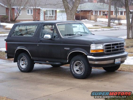 Black 1993 Ford Bronco parked in a driveway with houses in the background