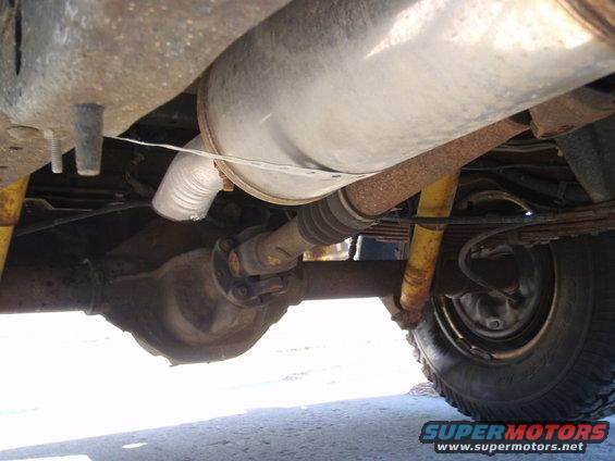Underside view of a vehicle's rear axle, driveshaft, exhaust, and suspension components