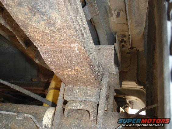 close-up of rusty leaf spring and shock absorber on underside of a vehicle