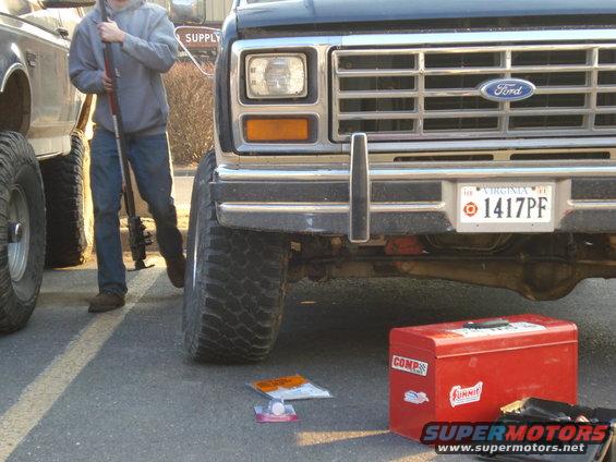 Front view of a black Ford truck with a chrome grille and bumper. Virginia license plate 1417PF. A red toolbox is on the ground