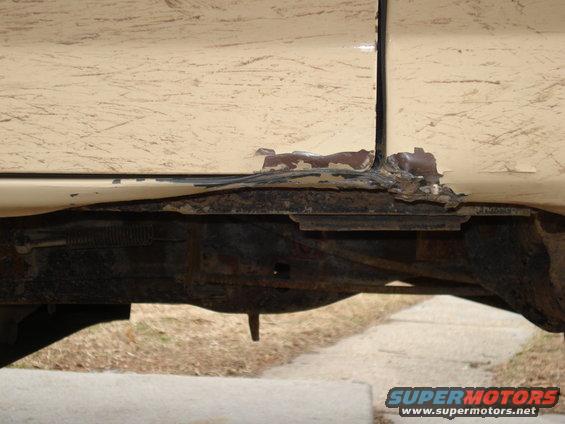 Close-up of rusted frame and lower body panel on a vehicle