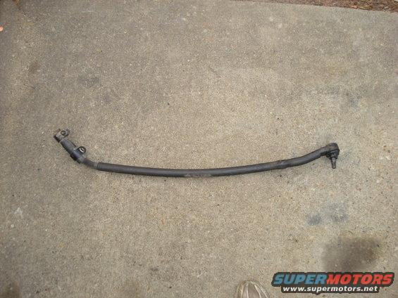 Steering linkage rod with ball joint ends, lying on concrete