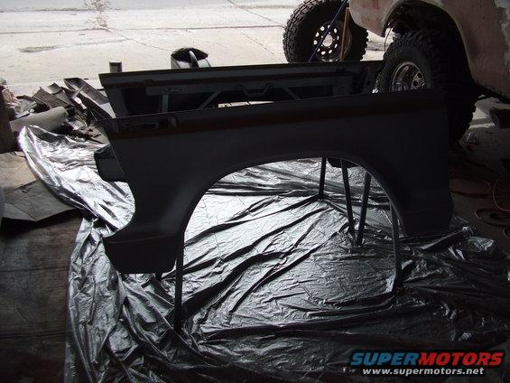 Dark gray Ford Bronco fender on stands over black plastic sheeting