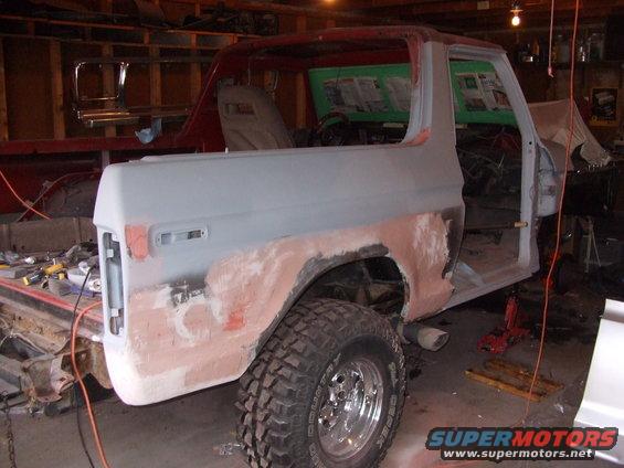 Ford Bronco bodywork in progress, primer applied to rear quarter panel, red roof, open doors