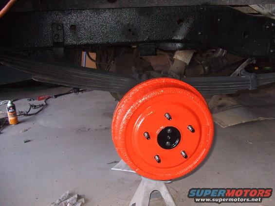 orange painted brake drum on jack stands, leaf springs above