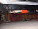 1979 Ford Bronco - The undercarriage of a vehicle is shown, a prominent exhaust system and an orange skid plate, with a red vehicle body visible in the backgr…