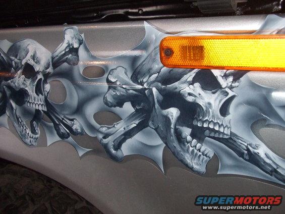 Silver fender with skull and crossbones airbrush art and an orange marker light