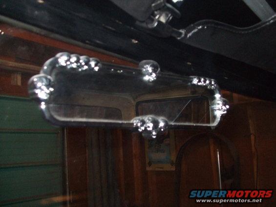 Chrome trim on interior rearview mirror, reflection shows part of the vehicle interior