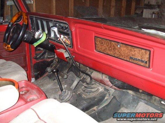 Red dashboard interior with wood-grain trim, "CUSTOM" badge, and dual gear shifters
