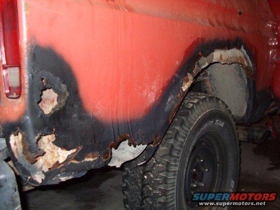 Red 1979 Ford Bronco rear quarter panel showing extensive rust damage around the wheel well