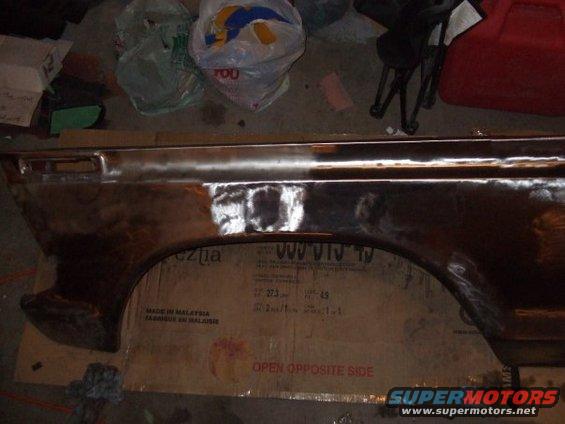 Rusty car fender with primer patches, viewed from the side
