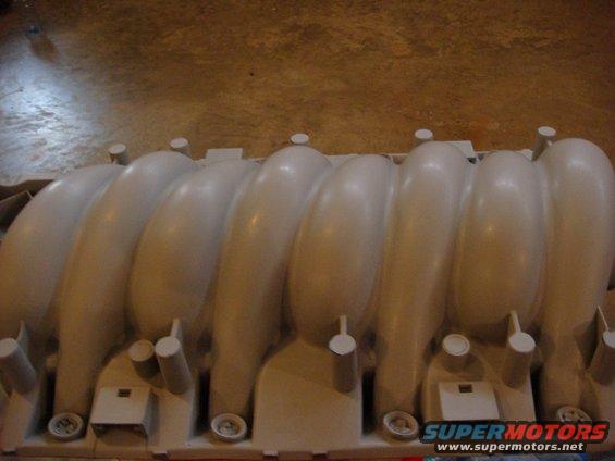 Beige plastic intake manifold with eight runners and mounting brackets