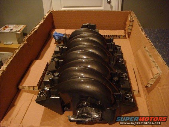 Black engine intake manifold in a cardboard box