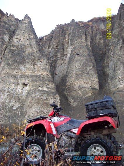 Red Arctic Cat ATV parked in front of a rocky cliff face. Date stamp reads 09/19/2009