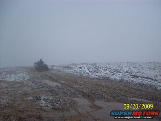 All-terrain vehicle on a muddy, snowy track under a foggy sky