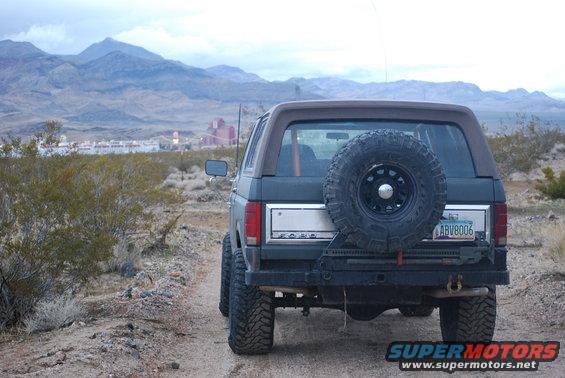 Rear view of a 1982 Ford Bronco parked on a dirt road with mountains in the background