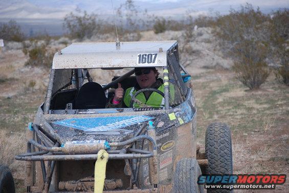 Driver in buggy gives thumbs up. Number 1607 visible on roof
