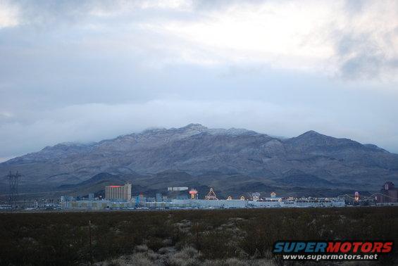 Desert landscape with mountains, buildings, and vegetation in the foreground