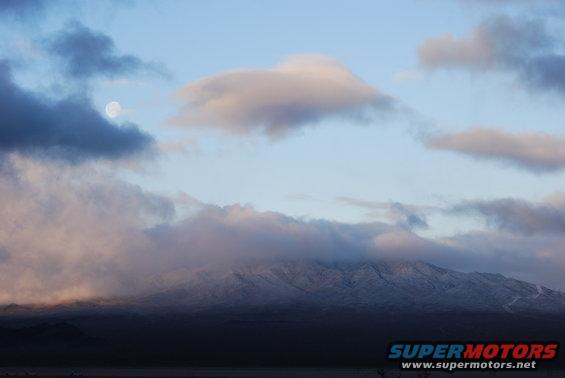 moon in sky over cloudy mountains