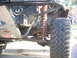 1992 Ford Ranger - Close-up of an off-road truck's suspension system, a large tire and a red coilover shock absorber. A Ford badge is visible on the skid plat…